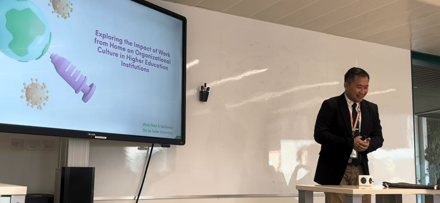 Imagen de un hombre de pie junto a una pantalla que muestra diapositivas, realizando una presentación durante el seminario.