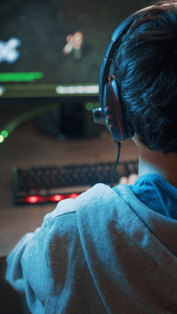 Young man seen from behind searching for information on a computer in a modern workspace.